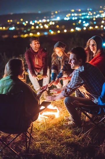 a group of people warming hands near a campfire at night