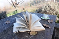 Open book and a coffee cup on an old picnic table 