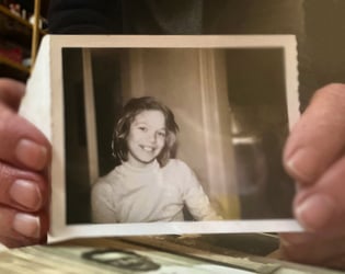Adult holding an old 4th grade photo of themselves