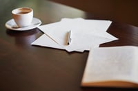 Handwritten thank you note, coffee cup and open book on a table