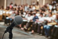 microphone over a blurred photo of a school board meeting