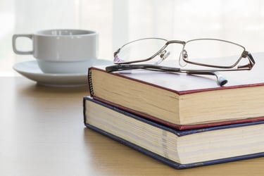 2 books with glasses on top and a cup a coffee 