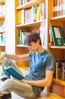male student reading in a library