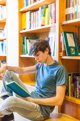 male student reading in a library